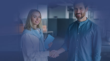 En man och en kvinna skakar hand och ler in i kameran